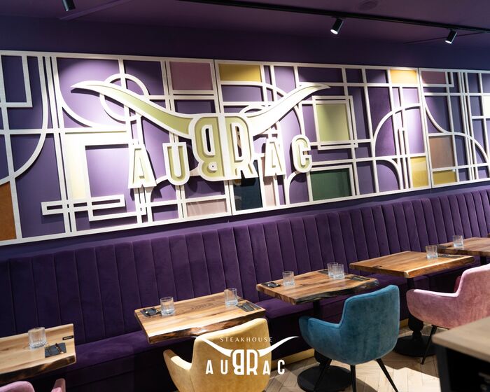 La salle et les banquettes aubergine du restaurant Aubrac